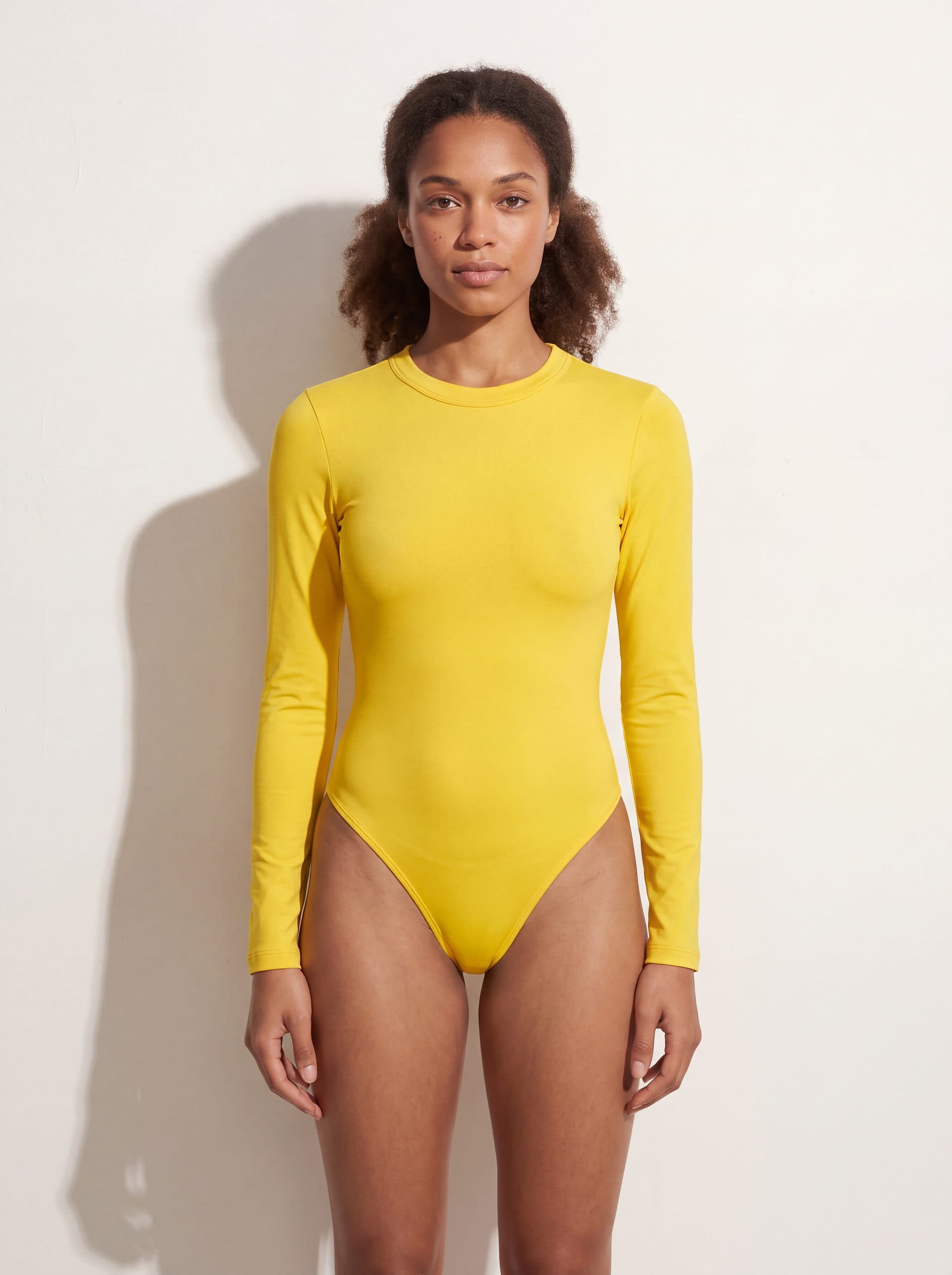 Body manga larga cuello redondo, en color amarillo, puesto en modelo