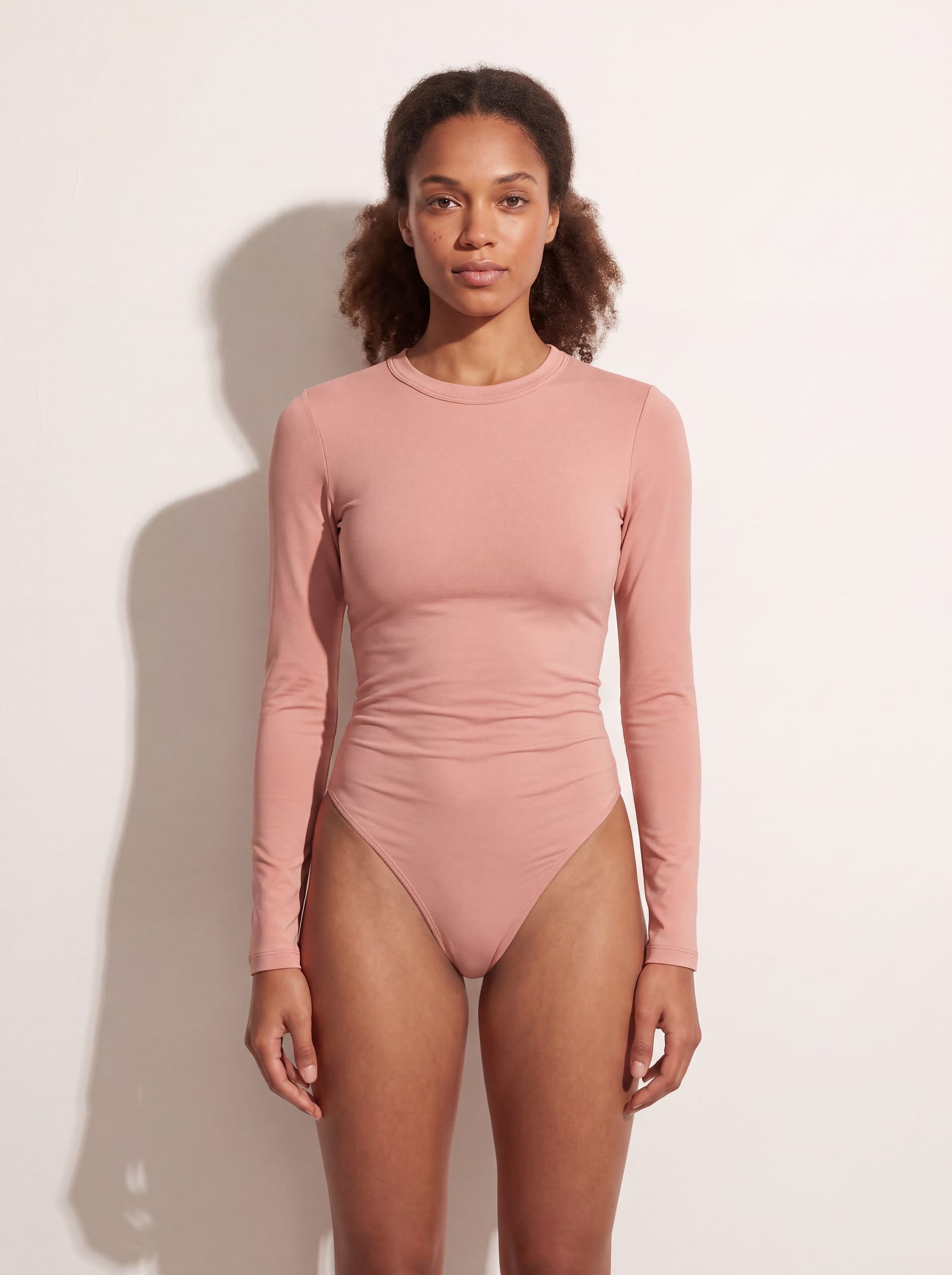 Body manga larga cuello redondo, en color rosado, puesto en modelo