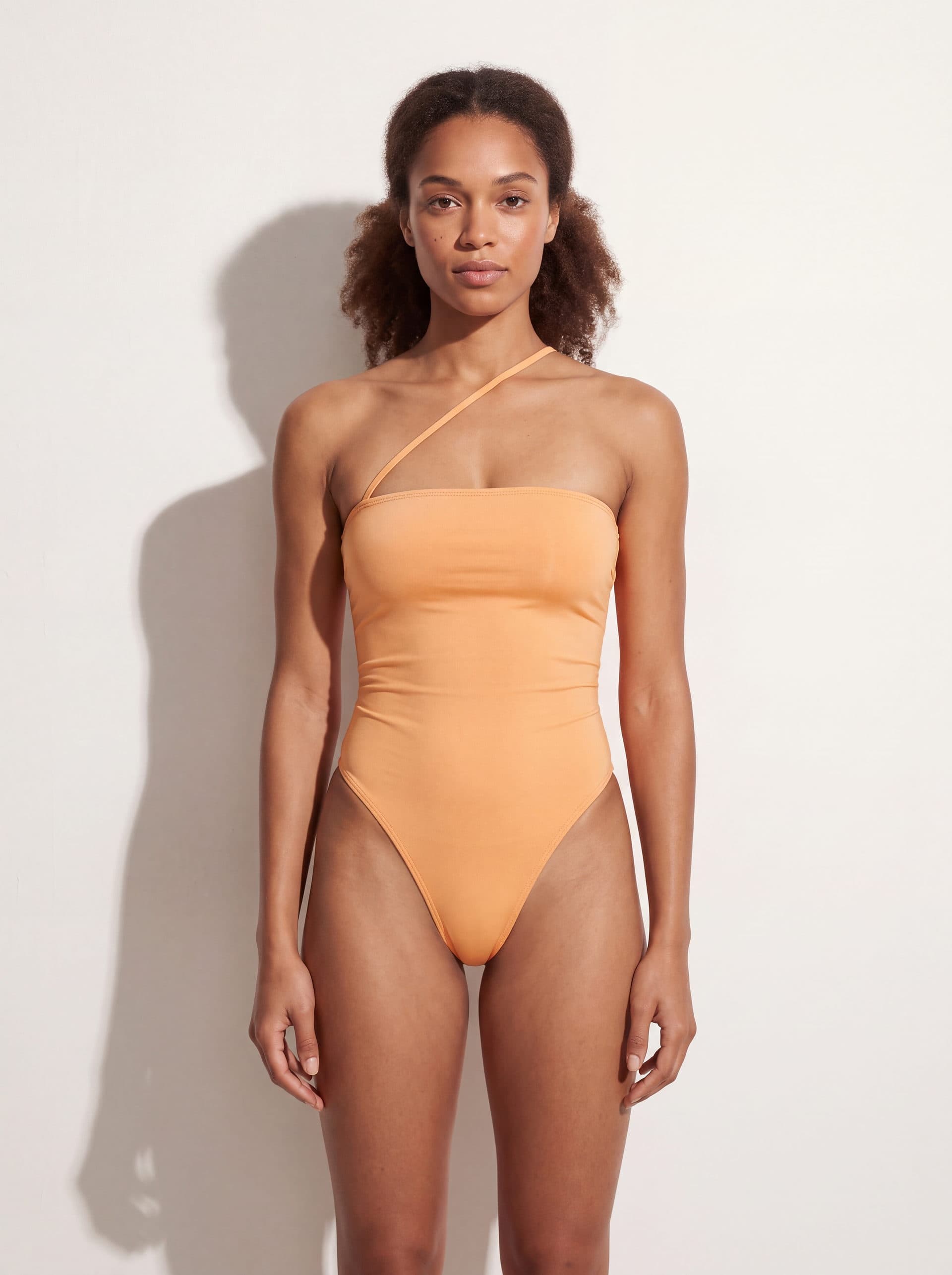 Body sin mangas con tirante diagonal, en color durazno, puesto en modelo