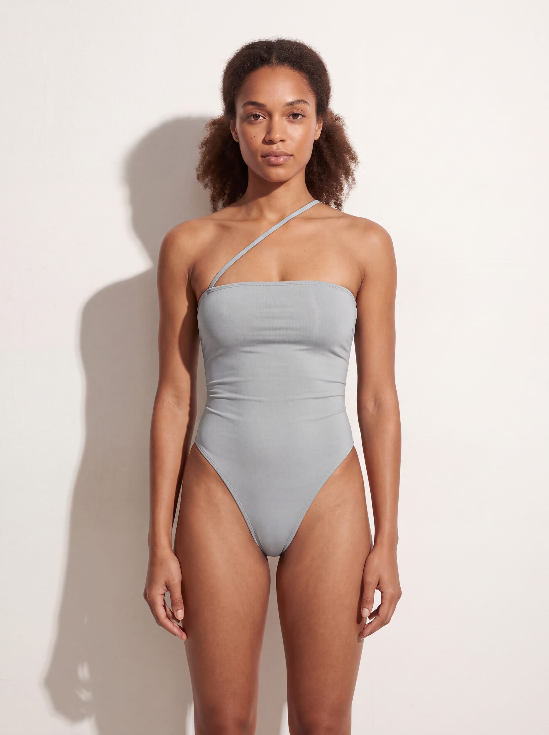 Body sin mangas con tirante diagonal, en color gris, puesto en modelo