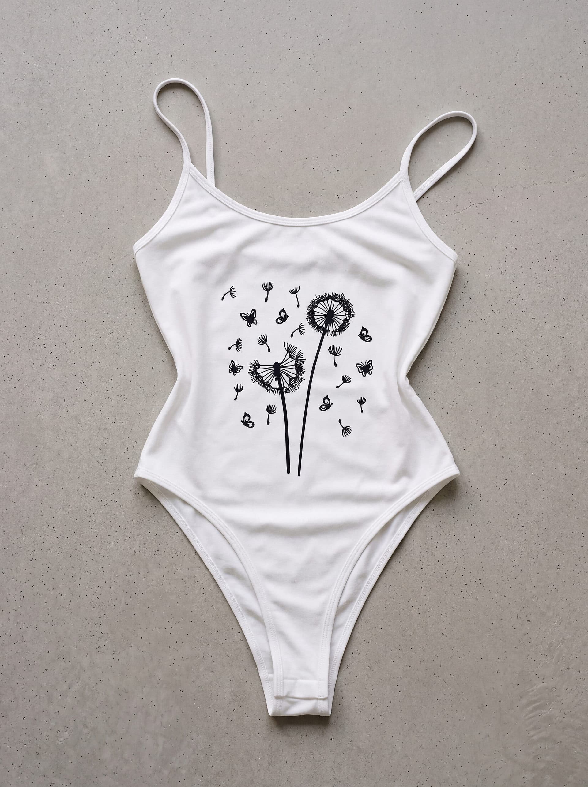 Body tirantes Diente de león mariposa, en color blanco, prenda sola sobre fondo de cemento