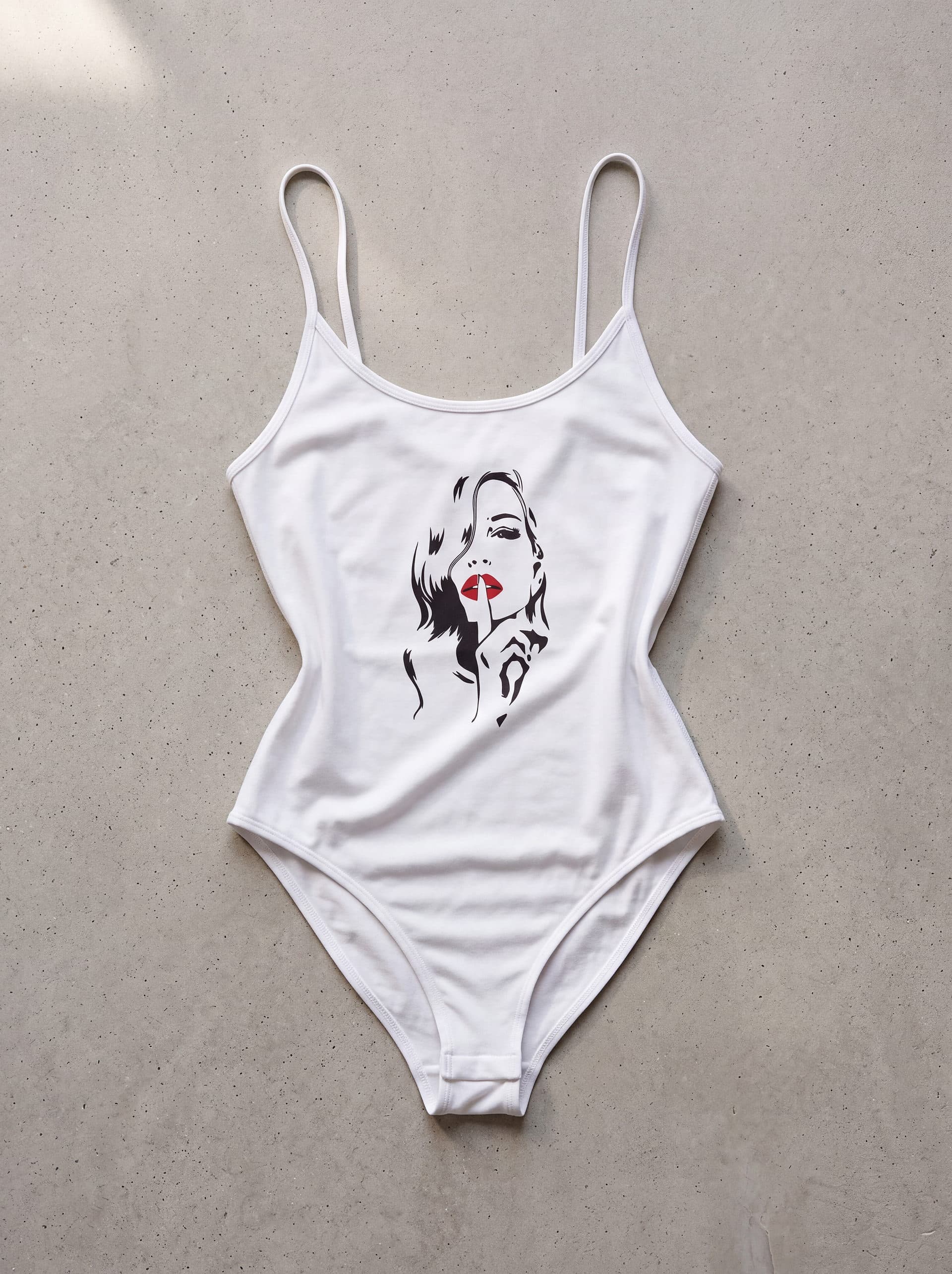 Body tirantes Mujer Shh, en color blanco, prenda sola sobre fondo de cemento