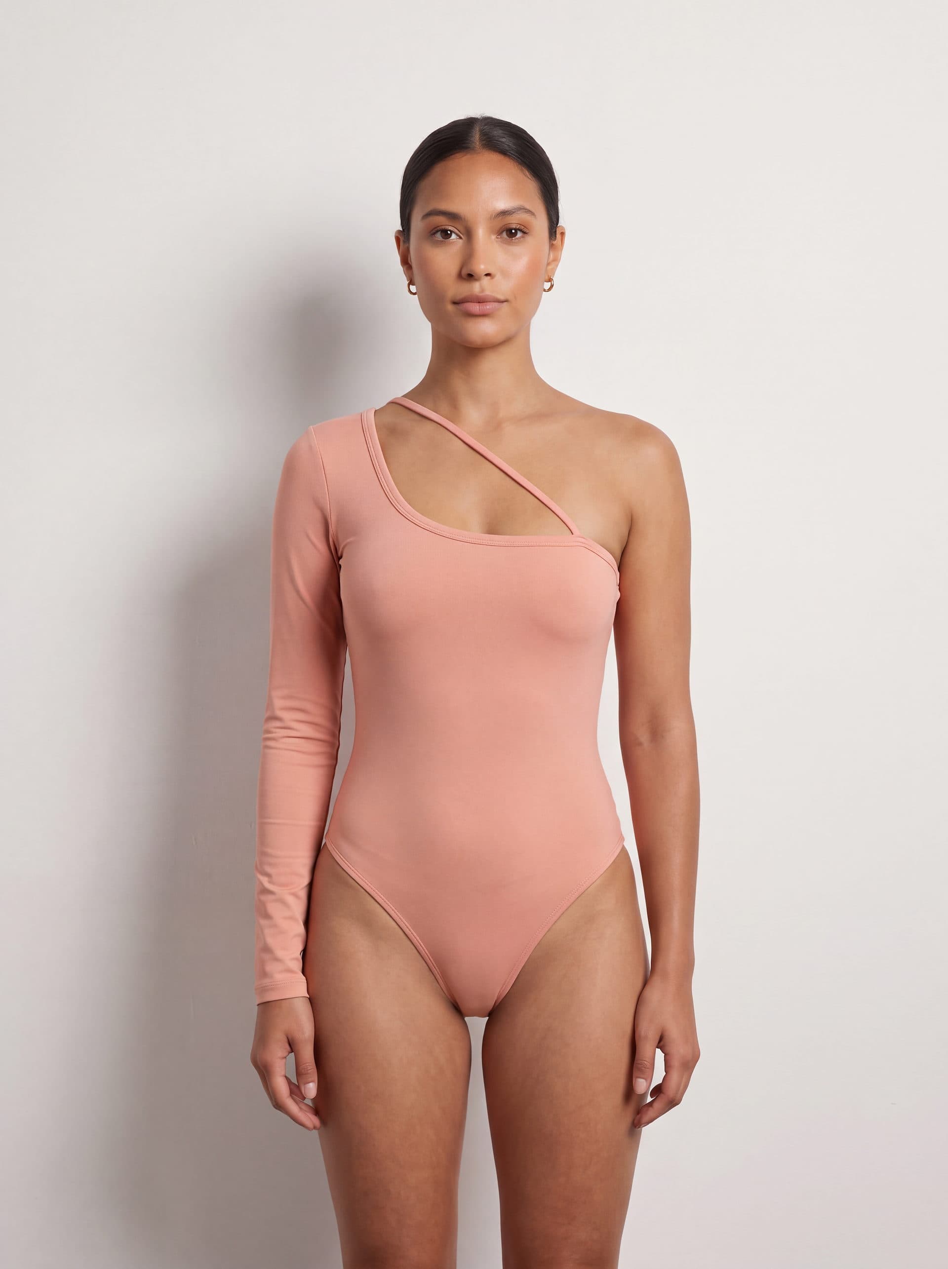 Body una manga larga con tirante diagonal, en color rosado, puesto en modelo