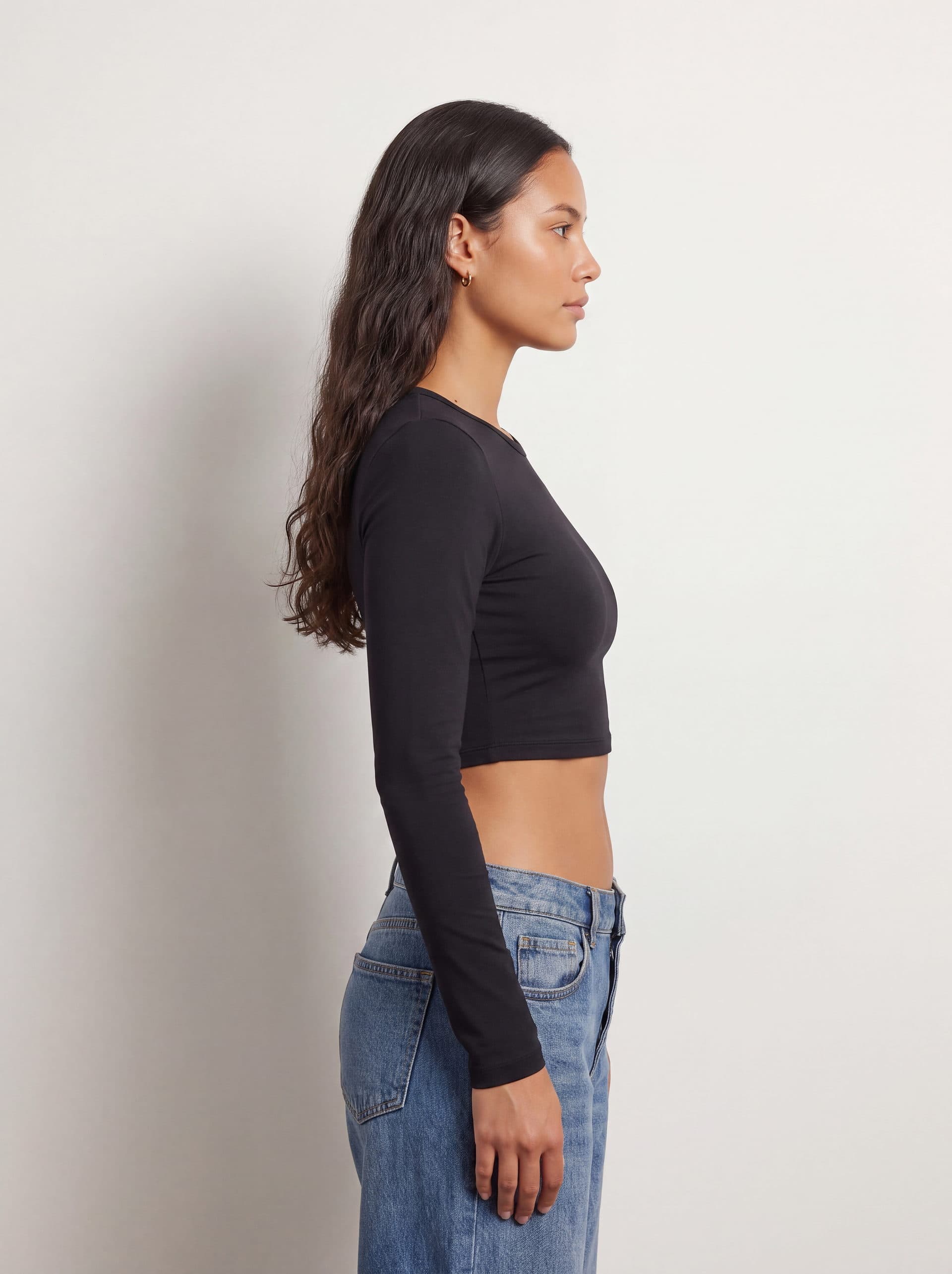 Crop top manga larga, en color negro, de perfil en modelo