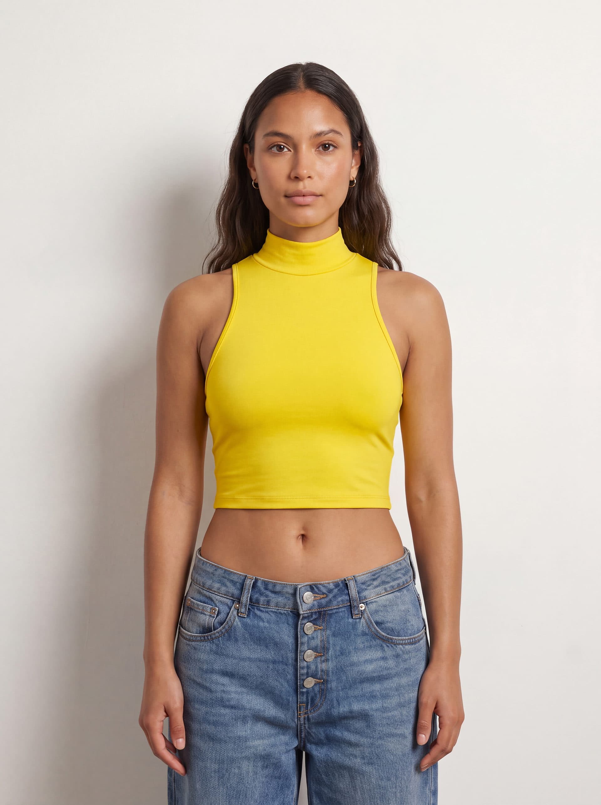 Crop top sin mangas cuello tortuga, en color amarillo, puesto en modelo