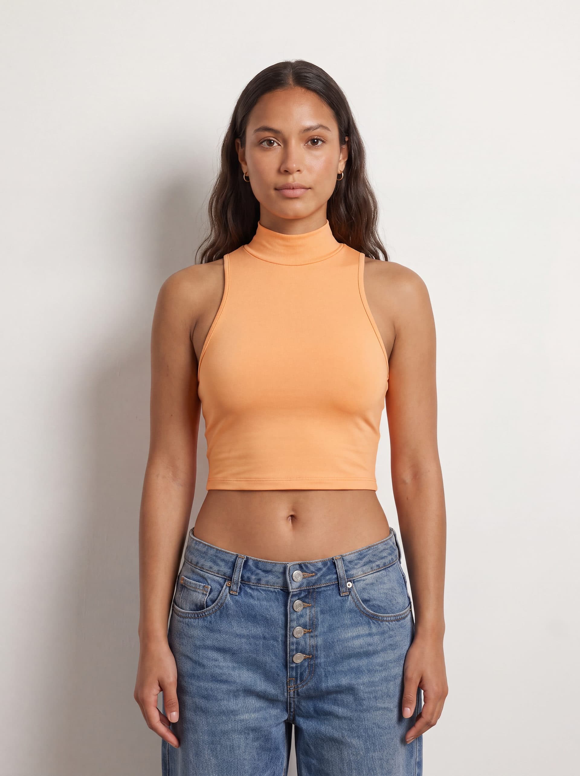 Crop top sin mangas cuello tortuga, en color durazno, puesto en modelo