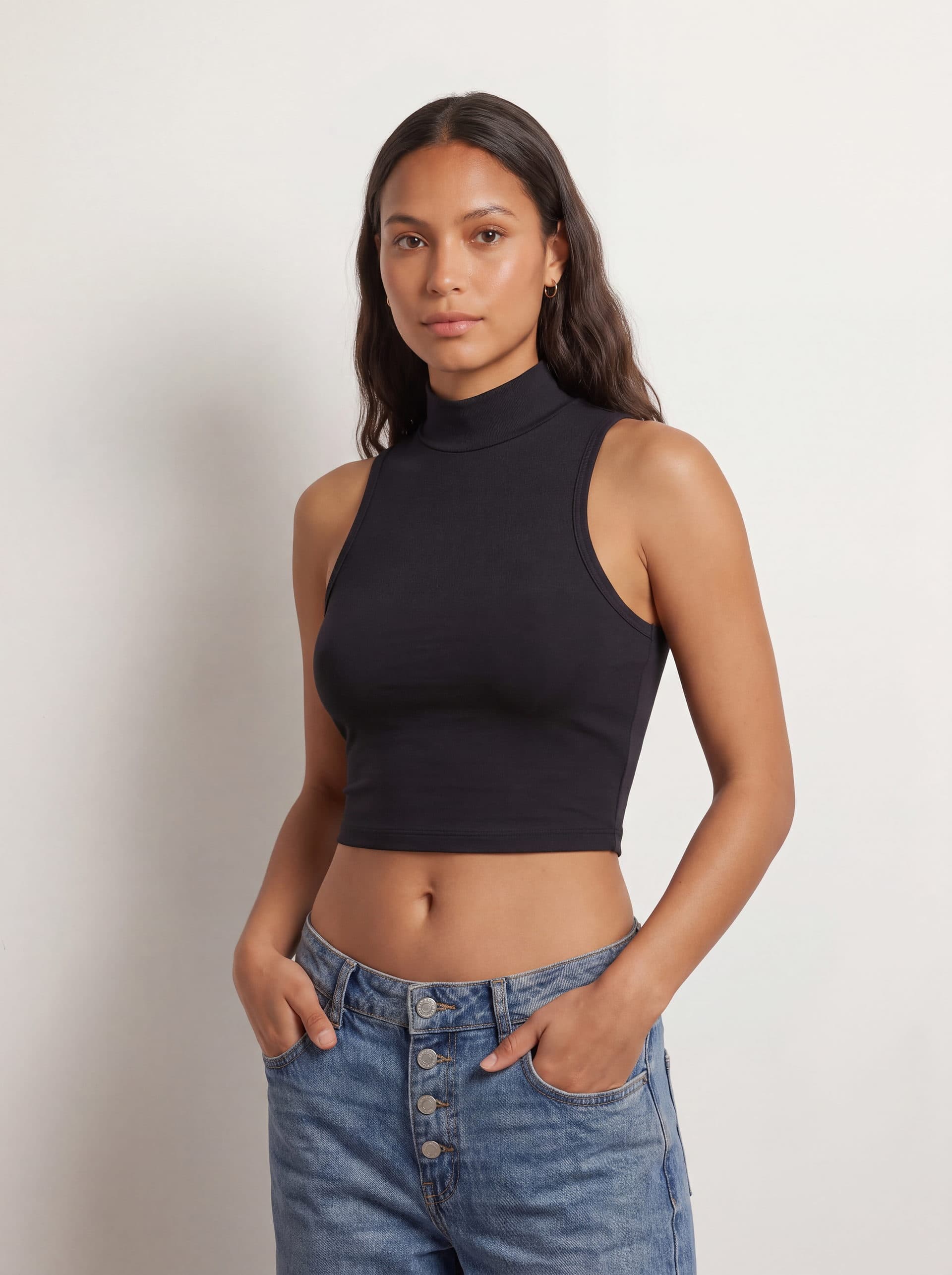 Crop top sin mangas cuello tortuga, en color negro, en modelo, vista de tres cuartos