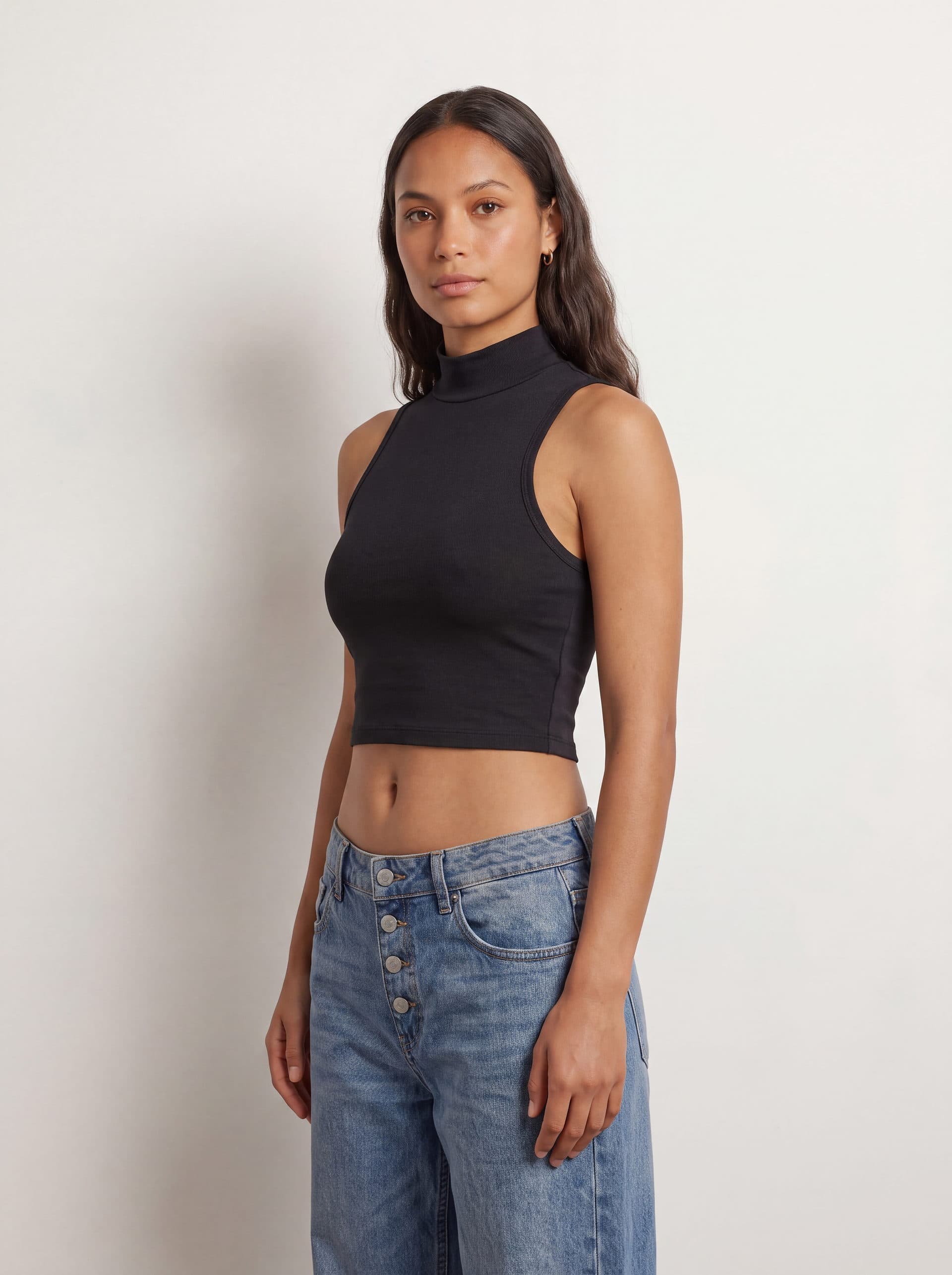 Crop top sin mangas cuello tortuga, en color negro, en modelo, vista de tres cuartos