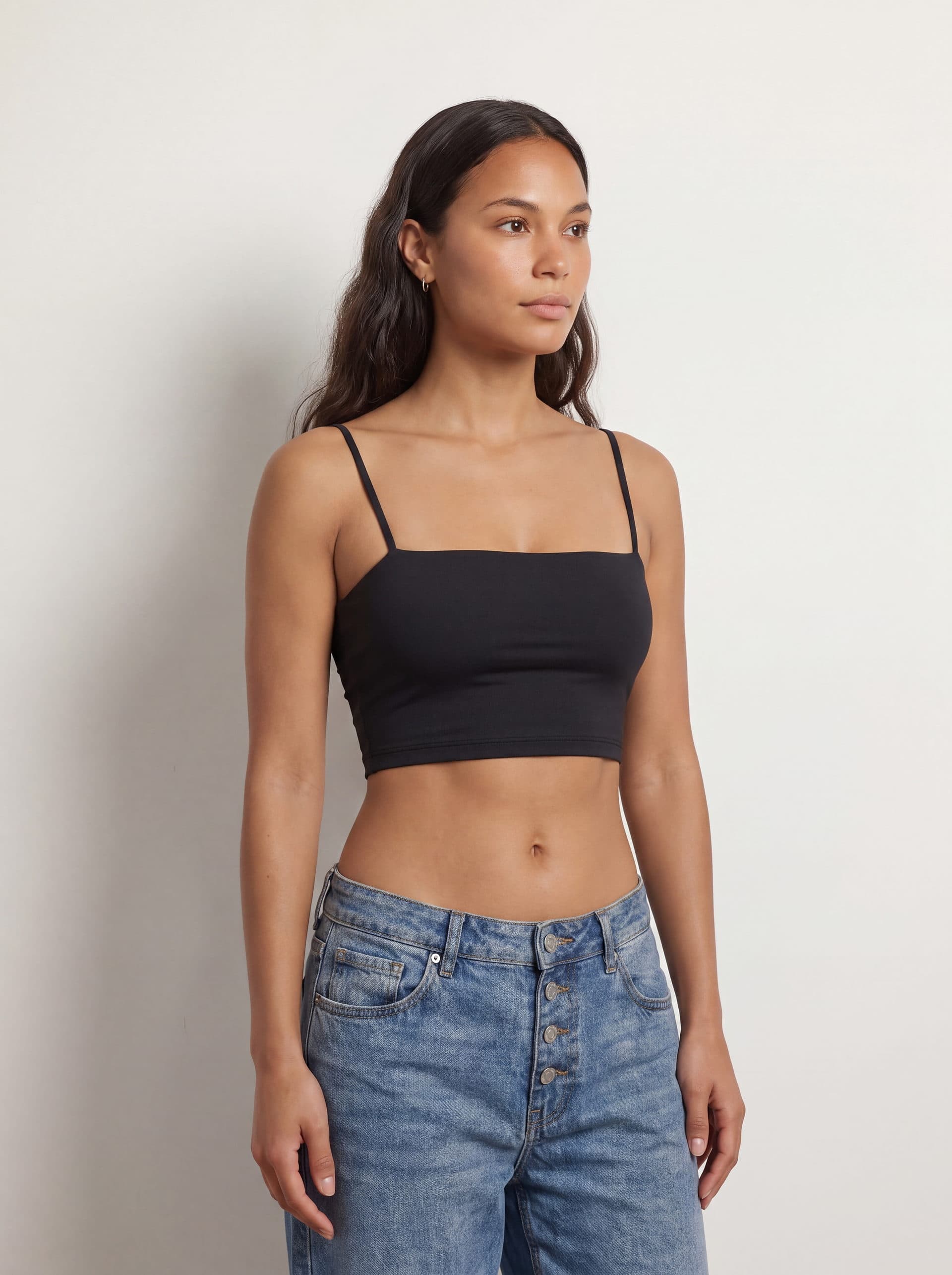 Crop top tirantes, en color negro, en modelo, vista de tres cuartos
