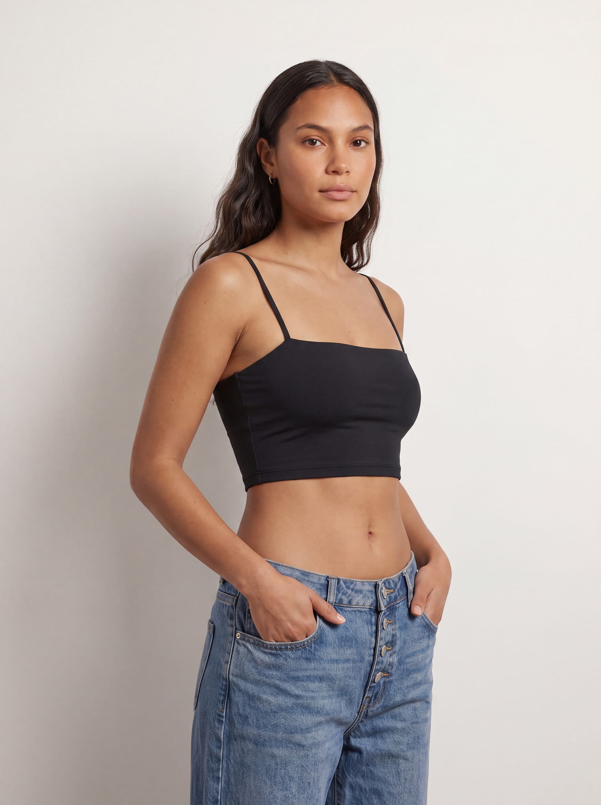 Crop top tirantes, en color negro, en modelo, vista de tres cuartos
