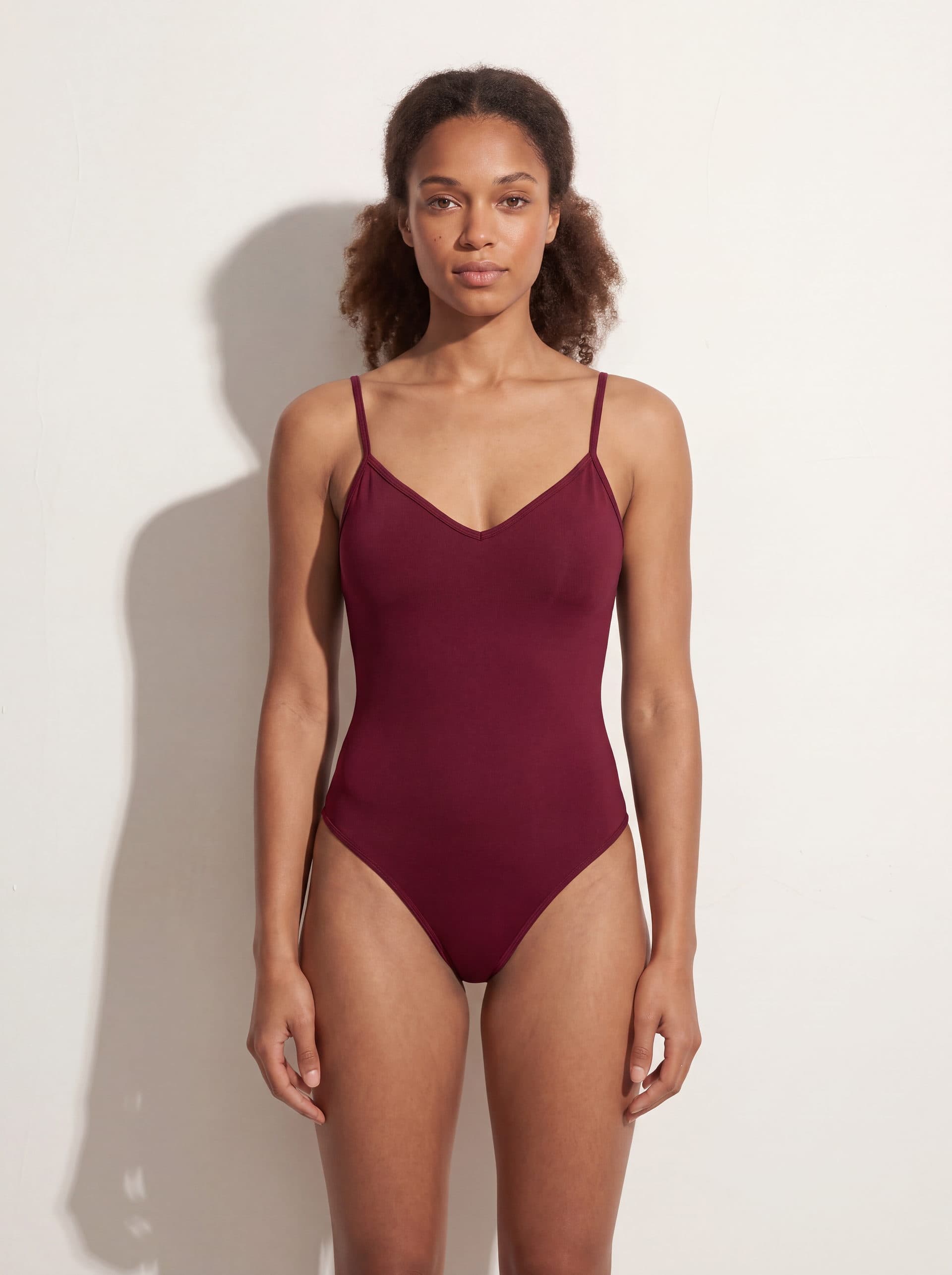Body para dama con tirantes cuello V, en color vino tinto, puesto en modelo
