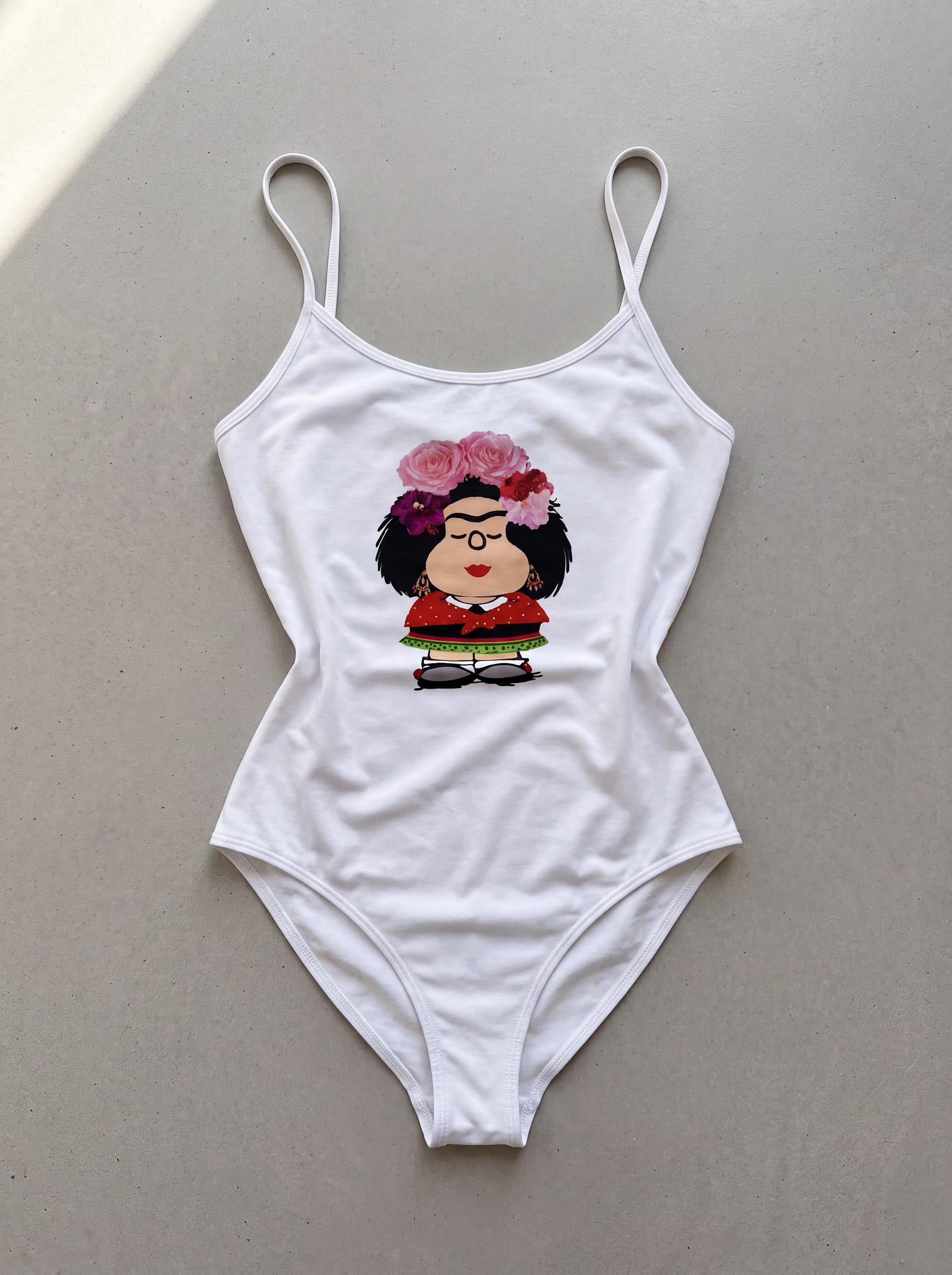 Body tirantes Mafalda Kahlo rosas, en color blanco, prenda sola sobre fondo de cemento