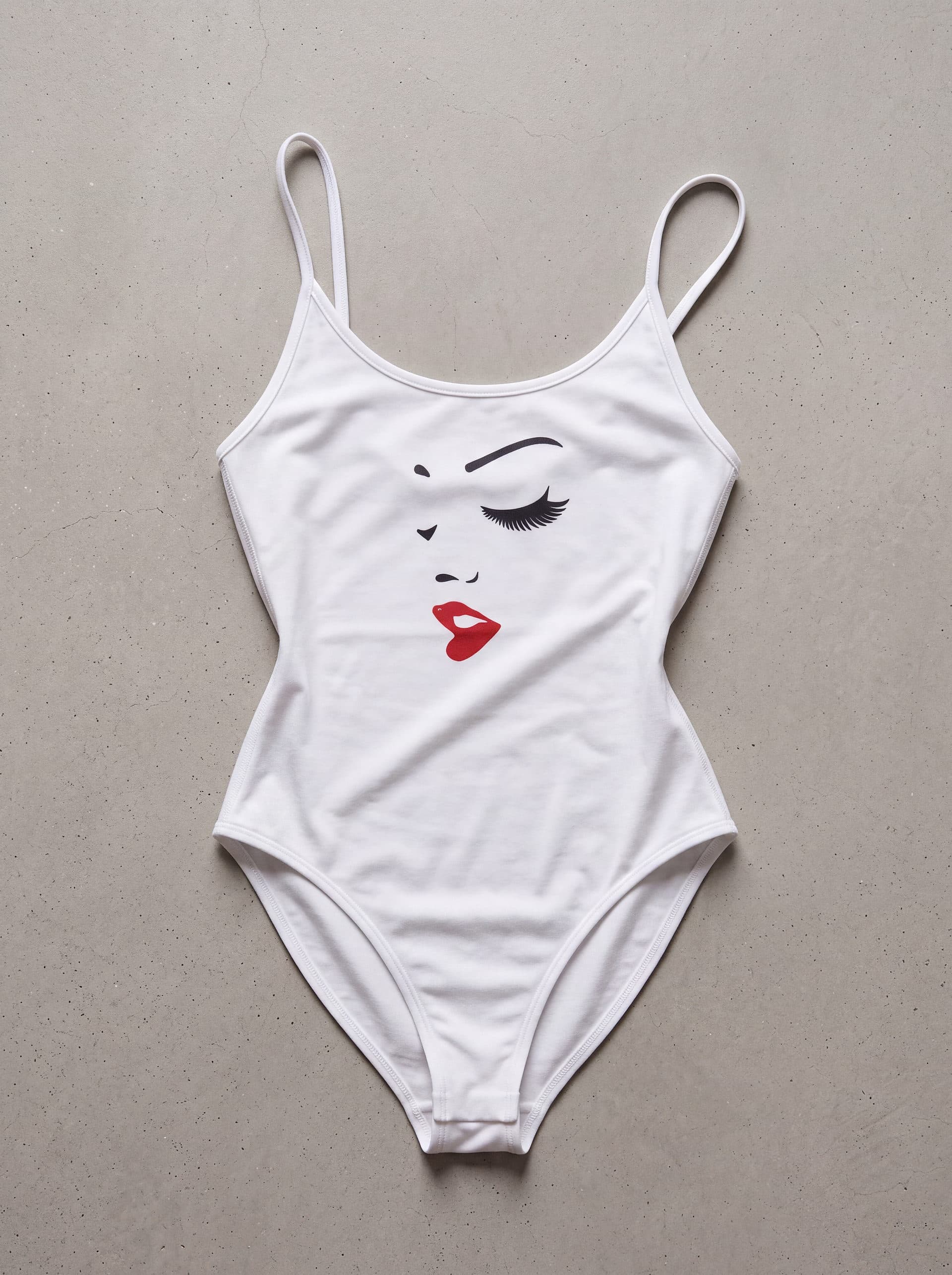Body tirantes Mujer Perfil, en color blanco, prenda sola sobre fondo de cemento