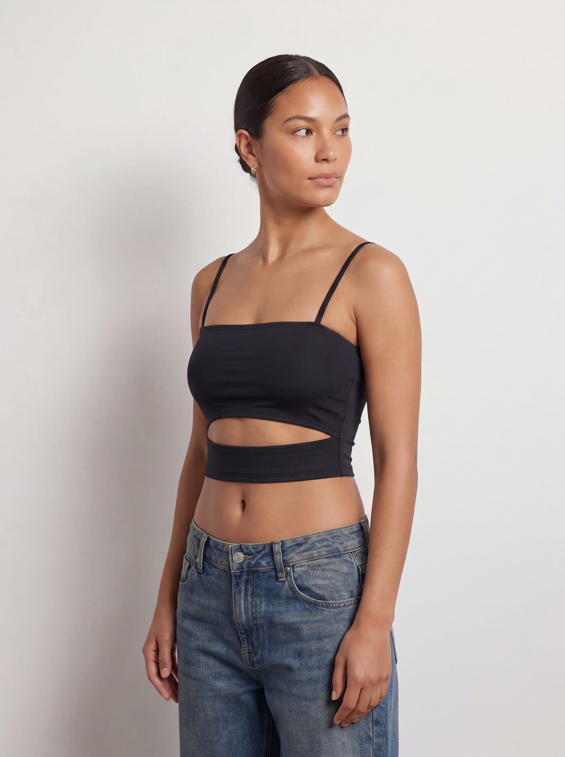 Crop top con abertura en cintura, en color negro, en modelo, vista de tres cuartos