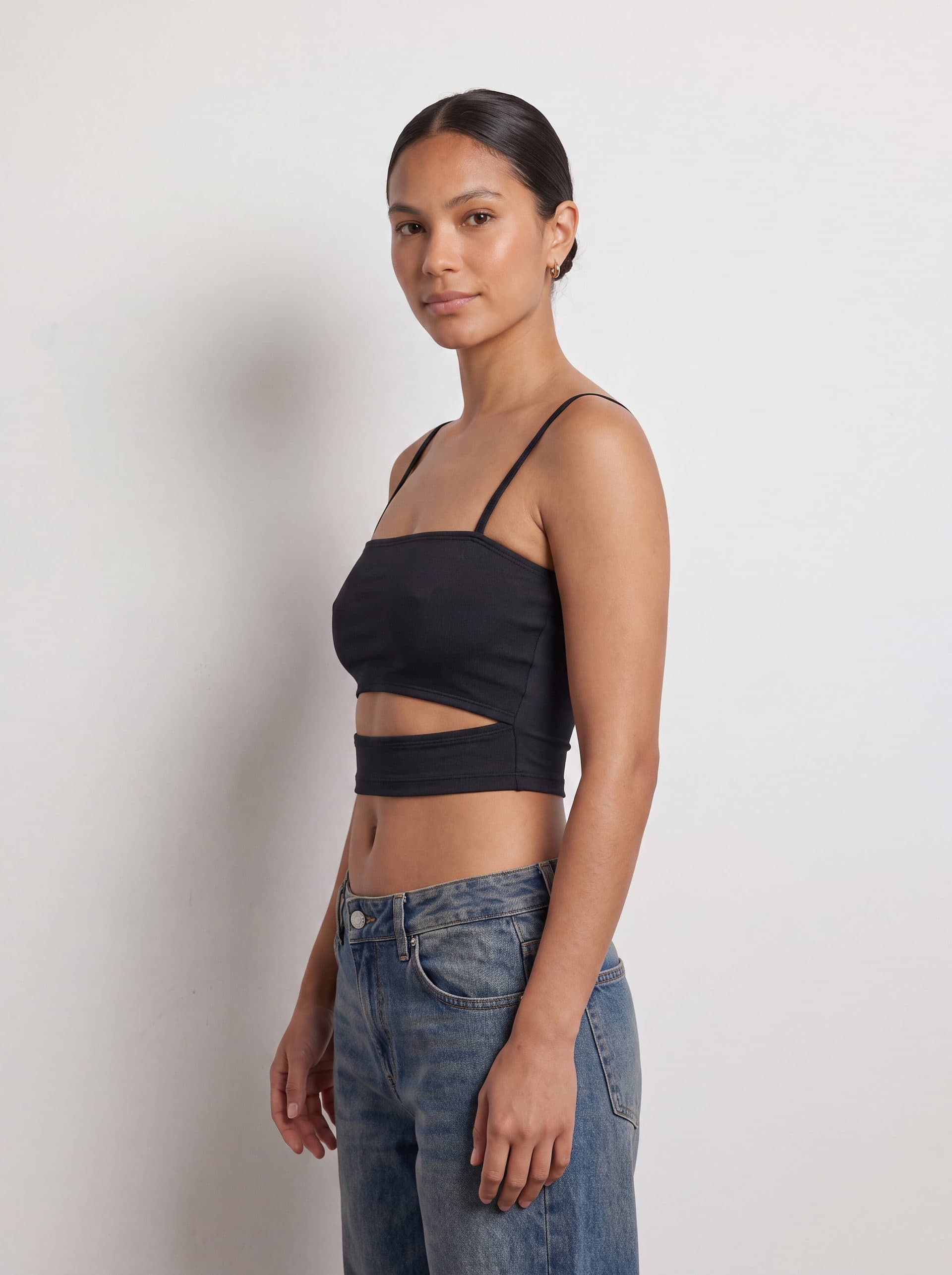 Crop top con abertura en cintura, en color negro, en modelo, vista de tres cuartos